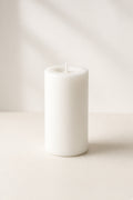 Smooth white unscented pillar candle on cream background